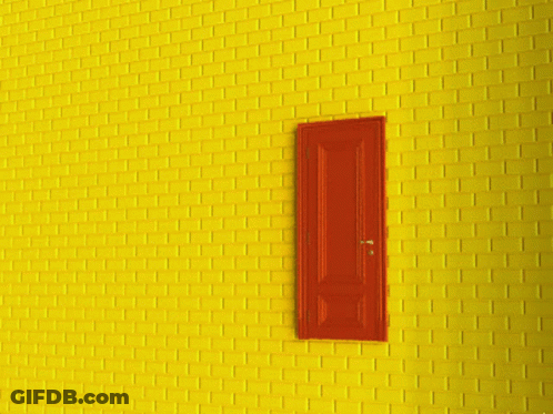 A Yellow Brick Wall With A Red Door That Is Open GIF