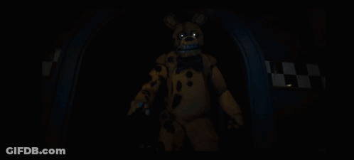 A Yellow Bunny With A Blue Bow Tie Is Standing In A Dark Room GIF