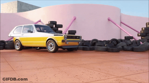 A Yellow Car Is Parked In Front Of A Pink Wall Surrounded By Tires GIF