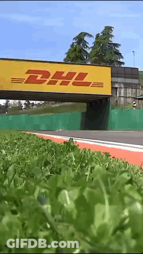 A Yellow Dhl Sign Is Above A Grassy Area GIF