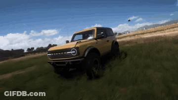 A Yellow Ford Bronco Is Driving Down A Grassy Hill GIF
