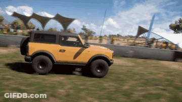 A Yellow Jeep Is Driving Through A Grassy Area GIF