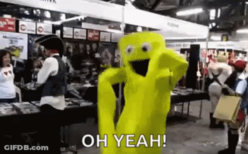 A Yellow Mascot In A Costume Is Dancing In A Room With People . GIF