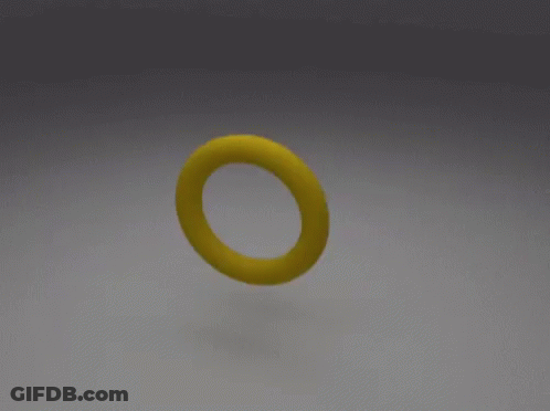 A Yellow Object With A Hole In The Middle Is Sitting On A White Surface GIF