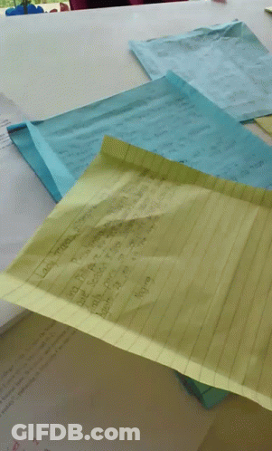 A Yellow Piece Of Paper Is Laying On Top Of A Pile Of Paper GIF