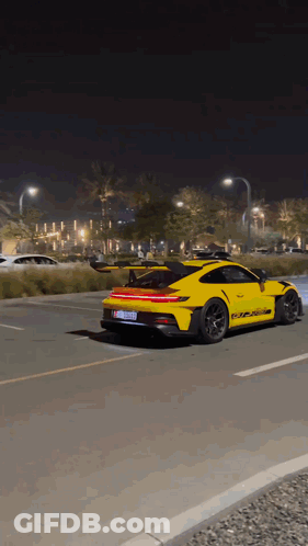 A Yellow Porsche 911 Gt3 Rs Is Driving Down A Road At Night GIF
