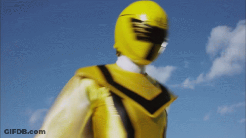 A Yellow Power Ranger Stands In Front Of A Blue Sky With Clouds GIF