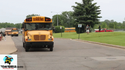 A Yellow School Bus Drives Down A Road GIF