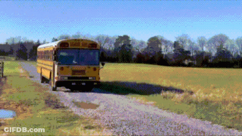 A Yellow School Bus Driving Down A Dirt Road GIF