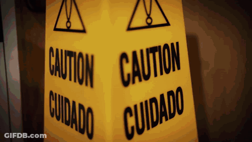 A Yellow Sign That Says Caution And Cuidado GIF