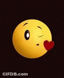 A Yellow Smiley Face Is Blowing A Kiss With A Red Heart On Its Nose . GIF