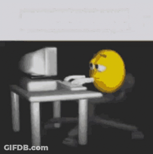 A Yellow Smiley Face Is Sitting In Front Of A Computer . GIF