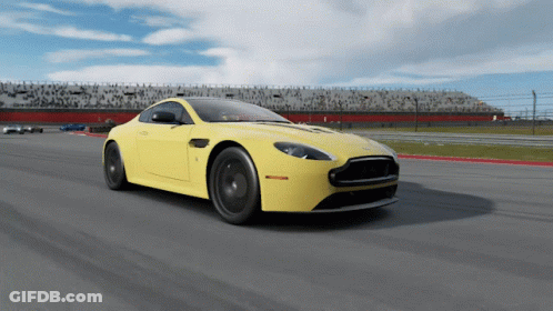 A Yellow Sports Car Is Driving Down A Track GIF