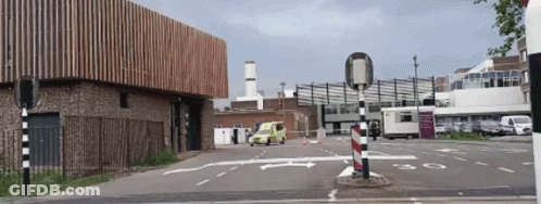 A Yellow Van Is Parked In A Parking Lot Near A Building GIF