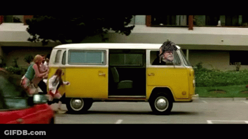 A Yellow Van With A Man In The Driver 'S Seat Is Driving Down The Street GIF