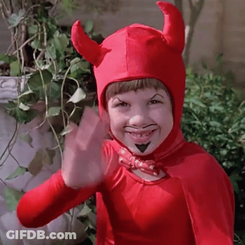 A Young Boy Dressed In A Devil Costume Is Waving . GIF