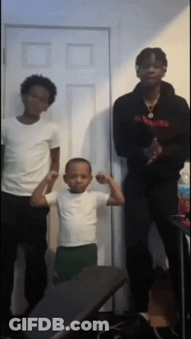 A Young Boy Flexes His Muscles While Standing Next To Two Men GIF