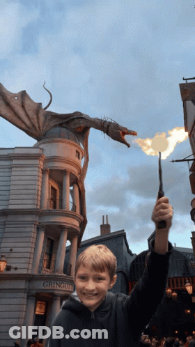 A Young Boy Holding A Wand In Front Of A Building That Says Gringotts GIF