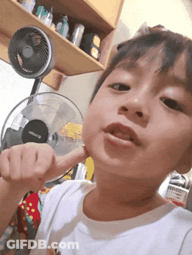 A Young Boy Holds His Fist Up In Front Of A Fan GIF