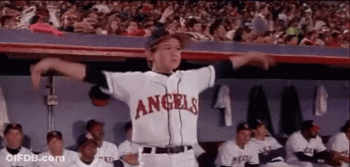 A Young Boy In A Baseball Uniform Is Dancing In The Dugout . GIF