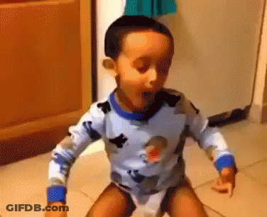 A Young Boy In A Blue And White Shirt Is Standing On A Toilet . GIF
