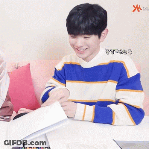 A Young Boy In A Blue And White Striped Sweater Is Sitting At A Table Holding A Piece Of Paper GIF