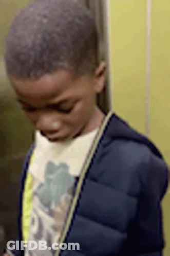 A Young Boy In A Blue Jacket Is Standing In An Elevator Looking Down . GIF