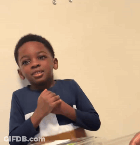 A Young Boy In A Blue Shirt Is Sitting At A Table GIF