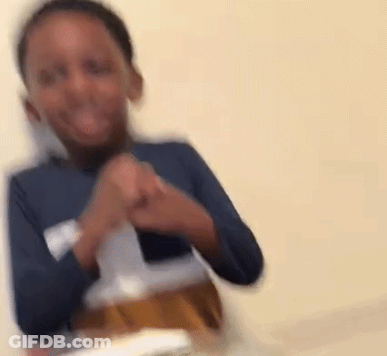 A Young Boy In A Blue Shirt Is Sitting At A Table With A Bottle Of Beer . GIF