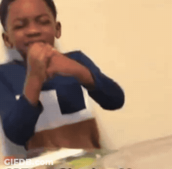 A Young Boy In A Blue Shirt Is Sitting At A Table With His Hands Folded . GIF