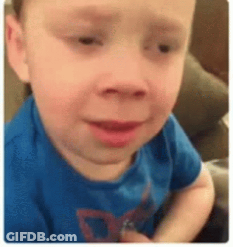 A Young Boy In A Blue Shirt Is Sitting On A Couch And Making A Funny Face . GIF