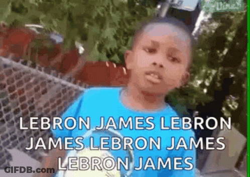A Young Boy In A Blue Shirt Is Standing Next To A Fence And Talking About Lebron James . GIF
