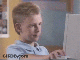 A Young Boy In A Blue Shirt Is Using A Laptop Computer GIF