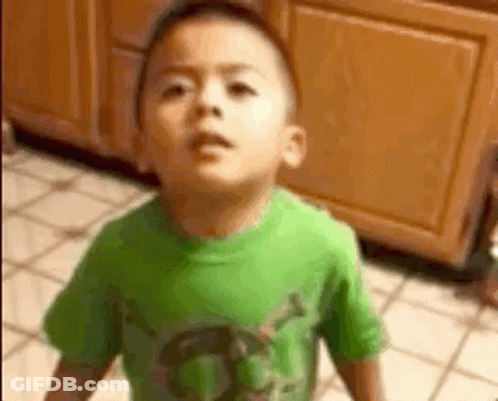 A Young Boy In A Green Shirt Is Standing On A Tiled Floor . GIF