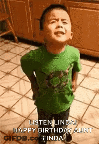A Young Boy In A Green Shirt Is Standing On A Tiled Floor And Making A Funny Face . GIF