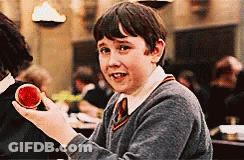 A Young Boy In A Harry Potter Uniform Is Holding A Red Object In His Hand . GIF