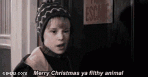 A Young Boy In A Hat Is Standing In Front Of A Door And Says `` Merry Christmas Ya Filthy Animal '' . GIF