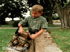 A Young Boy In A Plaid Shirt Is Holding A Large Bag GIF