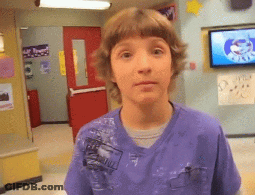 A Young Boy In A Purple Shirt Is Standing In Front Of A TV In A Hallway GIF
