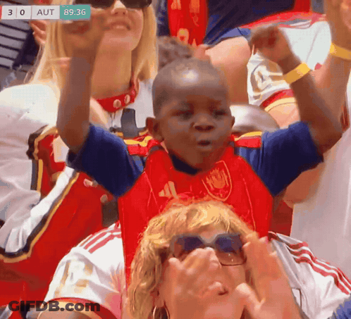 A Young Boy In A Red And Blue Shirt With The Number 41 On It Is Cheering In A Crowd GIF