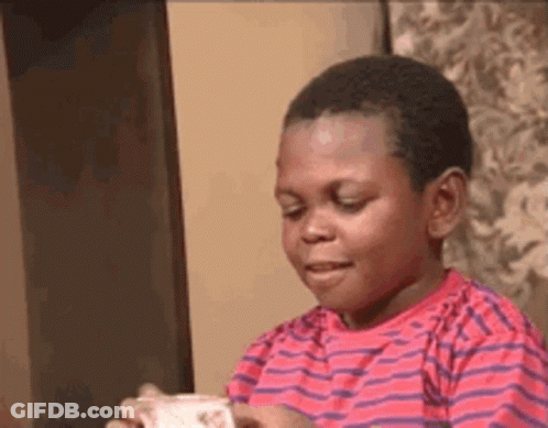 A Young Boy In A Red And Purple Striped Shirt Is Holding A Piece Of Paper In His Hand . GIF