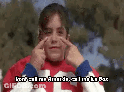 A Young Boy In A Red And White Jersey Is Making A Funny Face With His Hands . GIF