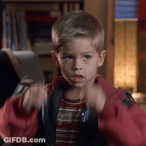 A Young Boy In A Red Jacket And Striped Shirt Is Making A Funny Face GIF