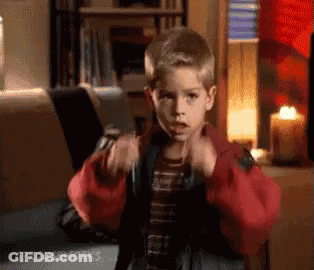 A Young Boy In A Red Jacket Is Sitting In Front Of A Laptop Computer In A Living Room . GIF