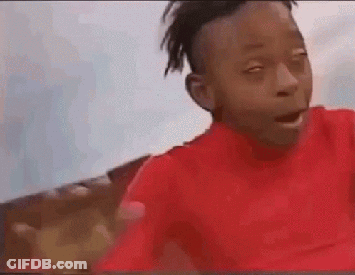 A Young Boy In A Red Shirt Is Making A Funny Face And Waving At The Camera . GIF