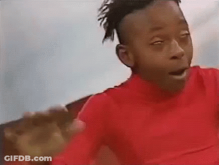 A Young Boy In A Red Shirt Is Making A Funny Face While Looking At The Camera . GIF