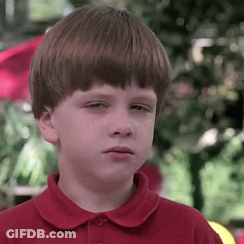 A Young Boy In A Red Shirt Is Making A Sad Face . GIF