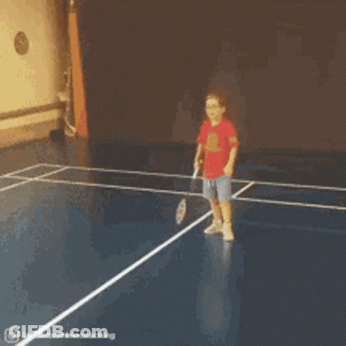 A Young Boy In A Red Shirt Is Playing Badminton On A Blue Court GIF