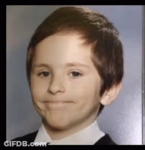 A Young Boy In A Suit And Tie Is Making A Silly Face . GIF