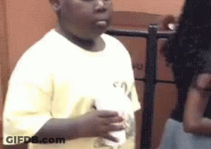 A Young Boy In A White Shirt Is Holding A Cup Of Milkshake . GIF